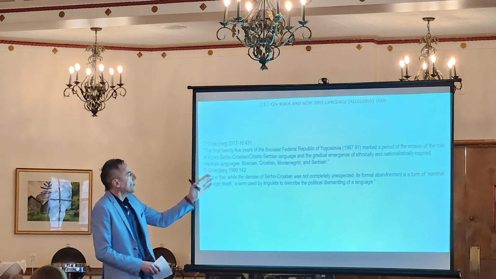 Dr. Belić at the projector screen reading from a selected quote