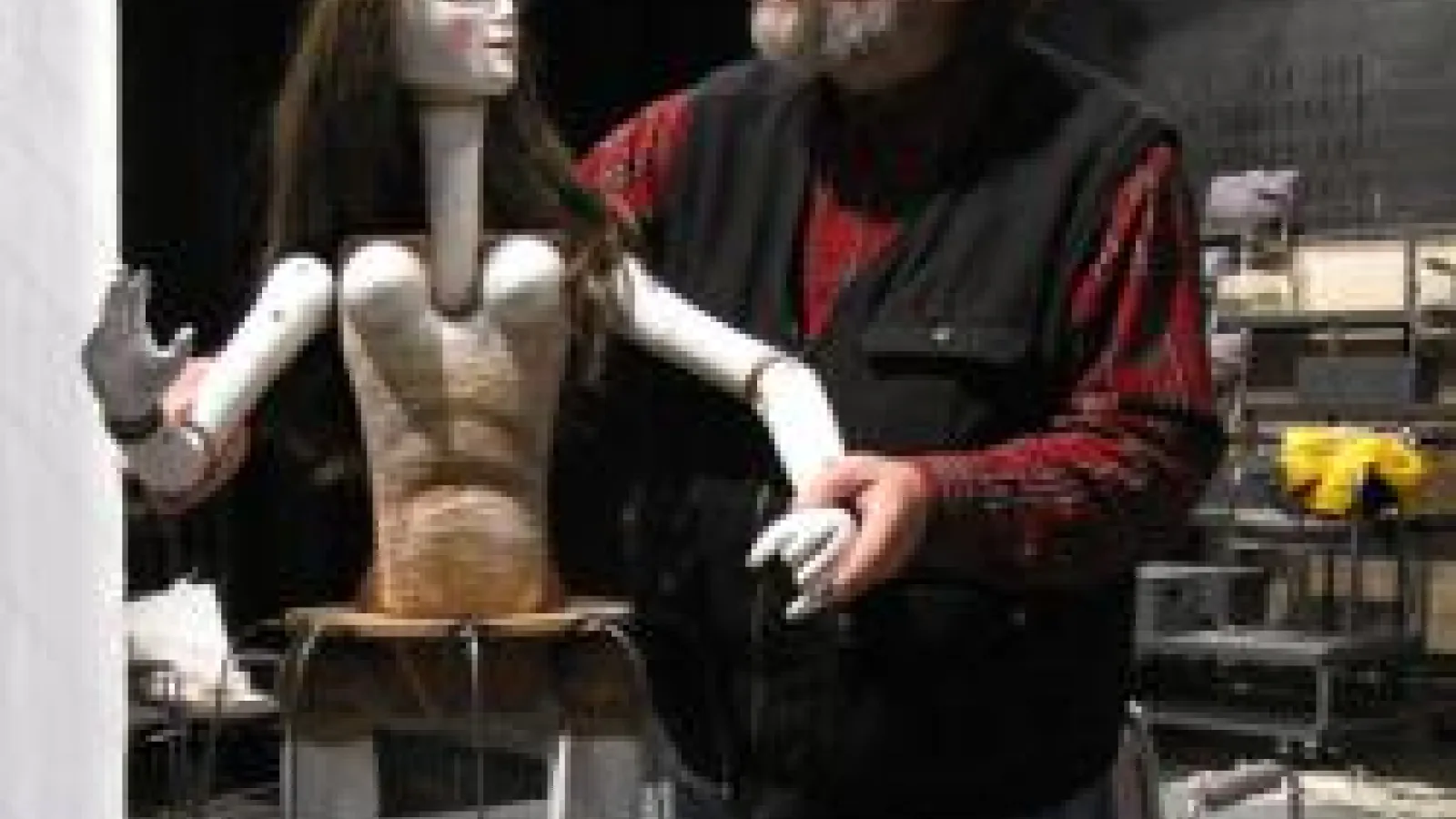 picture of professor with a art-piece, which is a doll of some sort