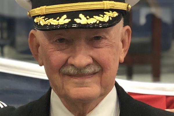 Captain James G Connell Junior in a Navy captain's cap and suit, smiling.